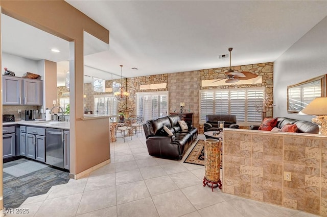 living area with light tile patterned floors, visible vents, and ceiling fan with notable chandelier