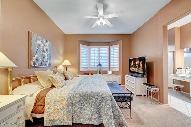 carpeted bedroom with ensuite bath, a ceiling fan, and tile patterned flooring