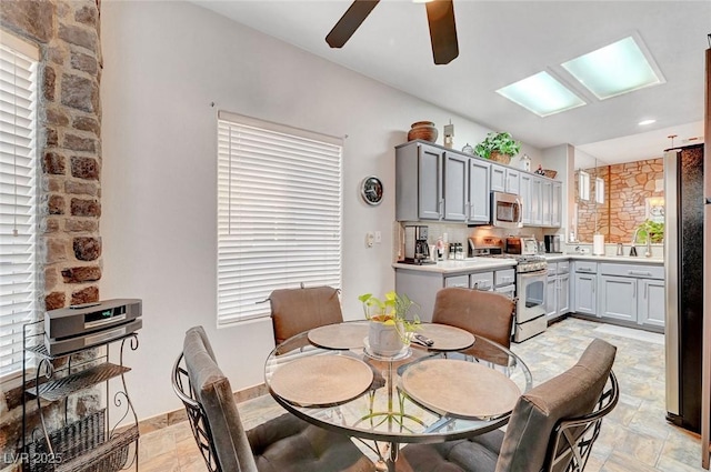 dining space featuring a ceiling fan, stone finish floor, and baseboards