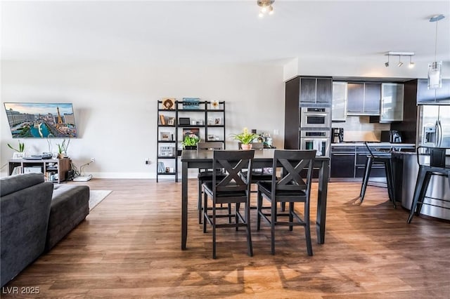 dining space featuring rail lighting and wood-type flooring