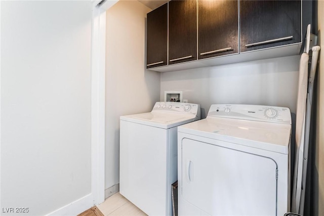 washroom with washing machine and clothes dryer, light tile patterned floors, and cabinets