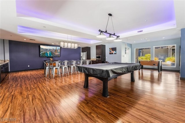 game room with hardwood / wood-style floors, indoor bar, a tray ceiling, and billiards