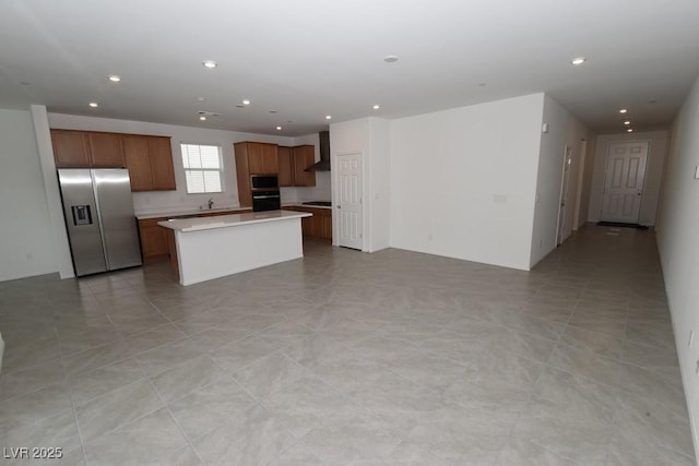 kitchen featuring stainless steel appliances, a kitchen island, wall chimney exhaust hood, and sink