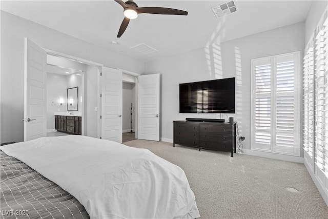 bedroom with connected bathroom, light colored carpet, and ceiling fan