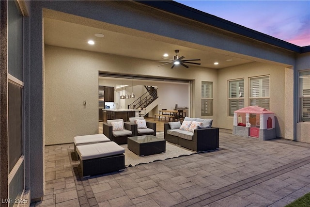 patio terrace at dusk with sink, an outdoor living space, and ceiling fan