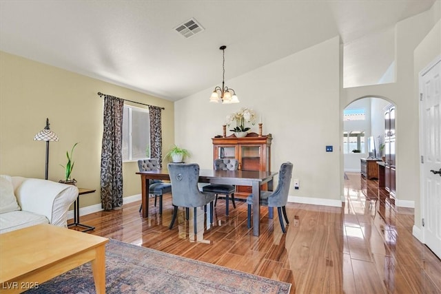 688 Quiet Stream Ct, Henderson, NV 89052 - dining room with arched walkways, light wood-style floors, a chandelier, baseboards, and vaulted ceiling