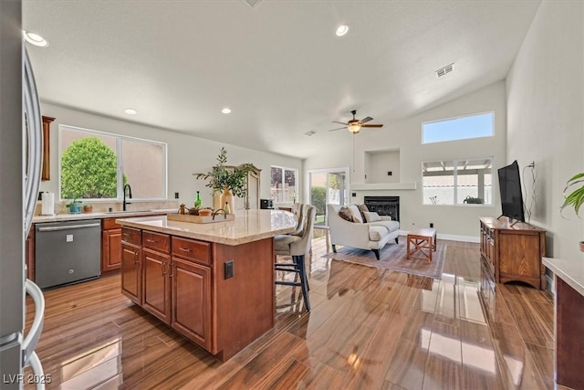 688 Quiet Stream Ct, Henderson, NV 89052 - kitchen featuring appliances with stainless steel finishes, a breakfast bar area, a ceiling fan, a glass covered fireplace, and a sink