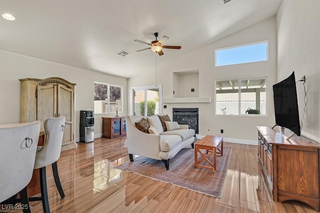 688 Quiet Stream Ct, Henderson, NV 89052 - living room featuring ceiling fan, a glass covered fireplace, vaulted ceiling, light wood-style floors, and baseboards
