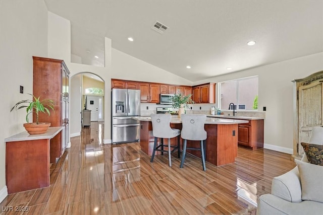 688 Quiet Stream Ct, Henderson, NV 89052 - kitchen featuring stainless steel appliances, light countertops, a center island, lofted ceiling, and wood finish floors