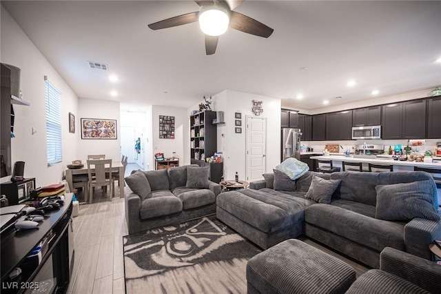 living room featuring light wood-type flooring and ceiling fan