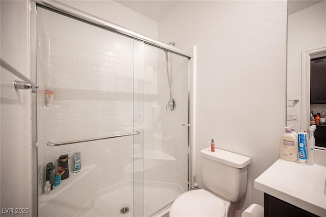 bathroom featuring an enclosed shower, vanity, and toilet