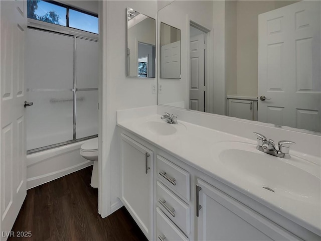 full bathroom with toilet, vanity, shower / bath combination with glass door, and hardwood / wood-style floors