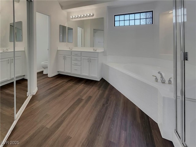 full bathroom featuring toilet, vanity, plus walk in shower, and wood-type flooring