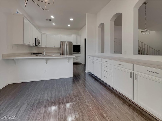 kitchen with stainless steel appliances, white cabinetry, and a breakfast bar