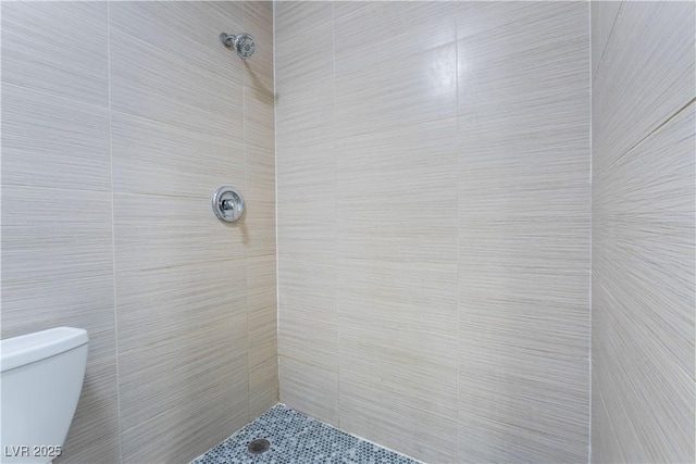 bathroom featuring tiled shower and toilet