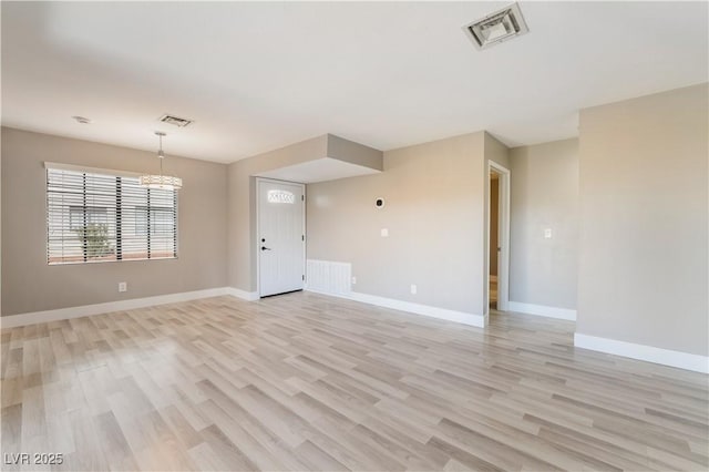 spare room featuring light wood-type flooring and a chandelier