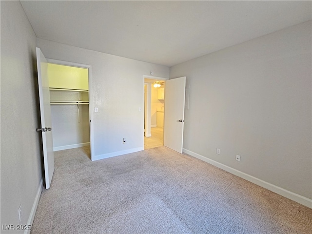 unfurnished bedroom featuring light carpet and a walk in closet