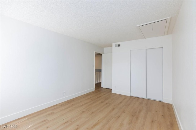 unfurnished bedroom with light hardwood / wood-style floors, a textured ceiling, and a closet