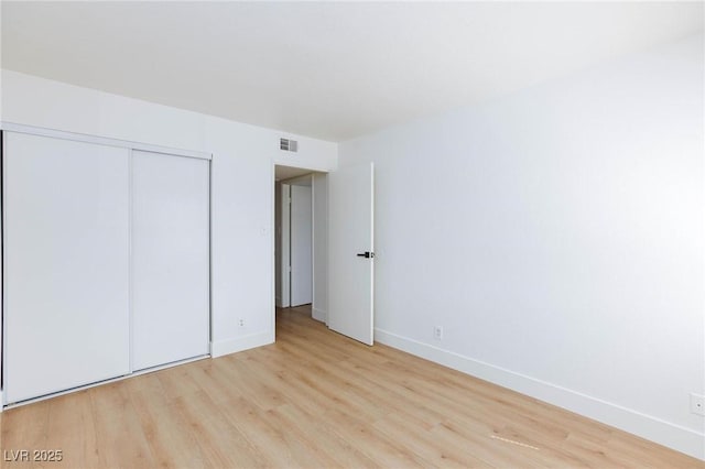 unfurnished bedroom with a closet and light hardwood / wood-style floors