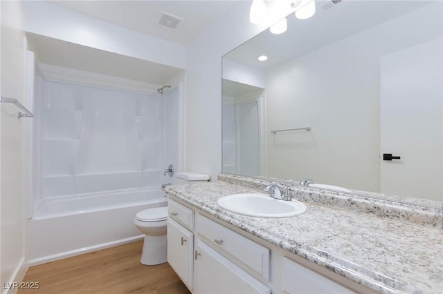 full bathroom featuring hardwood / wood-style floors, bathing tub / shower combination, vanity, and toilet