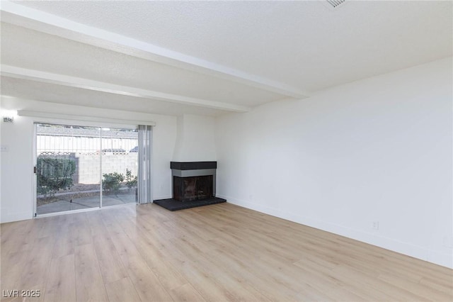 unfurnished living room featuring beam ceiling, light hardwood / wood-style floors, a textured ceiling, and a fireplace