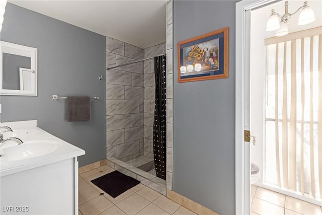 bathroom with a notable chandelier, vanity, tile patterned flooring, and tiled shower