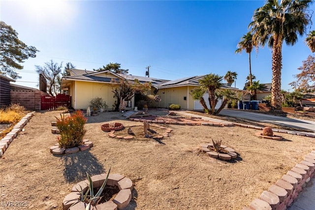 ranch-style house with solar panels and a fire pit