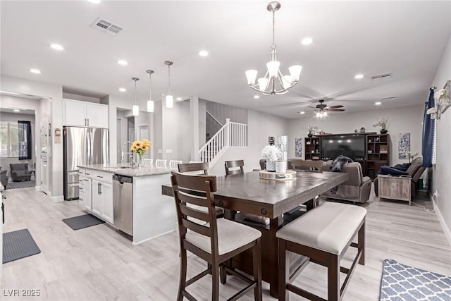 dining area with sink, a barn door, ceiling fan, and light hardwood / wood-style flooring