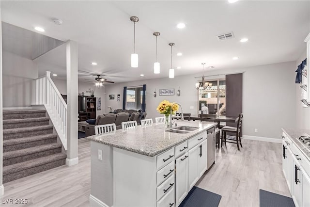 kitchen featuring decorative light fixtures, sink, a kitchen island with sink, and white cabinets