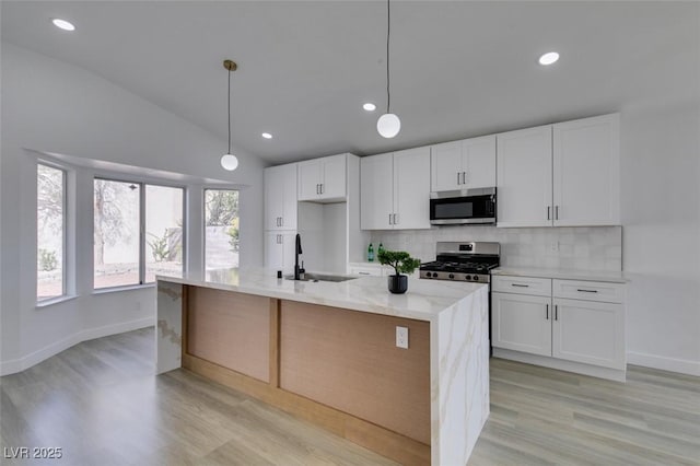 kitchen featuring sink, appliances with stainless steel finishes, a kitchen island with sink, and decorative light fixtures