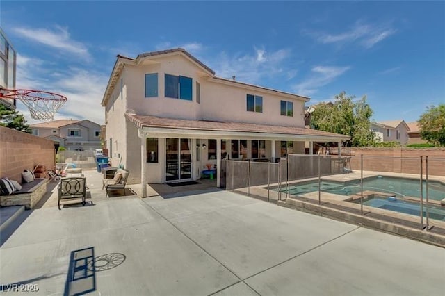 rear view of house with a patio and a pool with hot tub