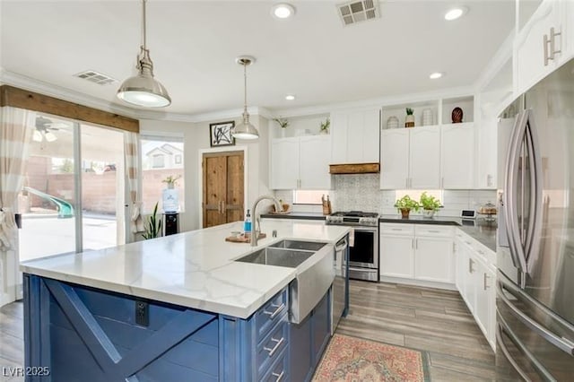 kitchen featuring stainless steel appliances, light stone countertops, white cabinets, blue cabinets, and pendant lighting