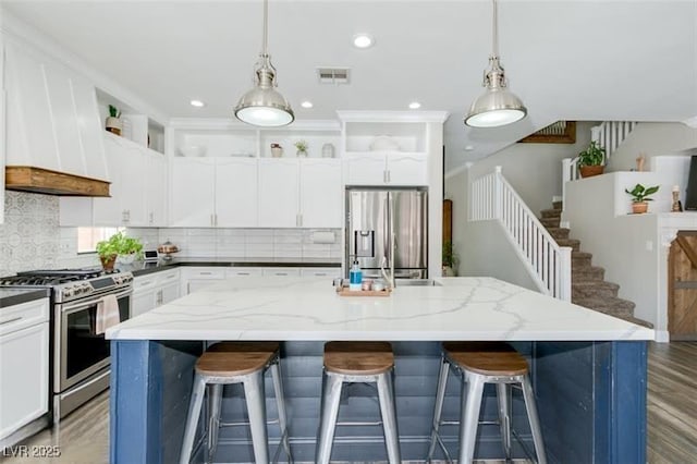 kitchen with hanging light fixtures, stainless steel appliances, a kitchen island, and white cabinets