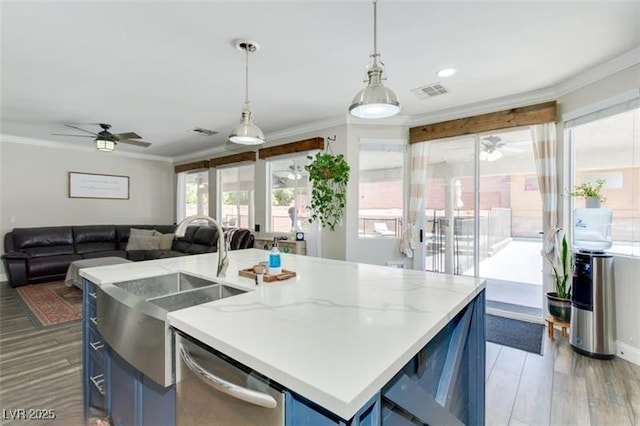 kitchen with blue cabinets, a center island with sink, pendant lighting, and dishwasher