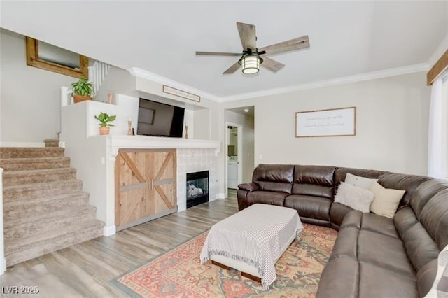 living room featuring wood-type flooring, ceiling fan, and crown molding