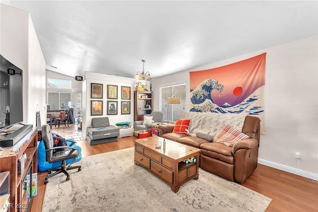 living room with light wood-style flooring, baseboards, and vaulted ceiling