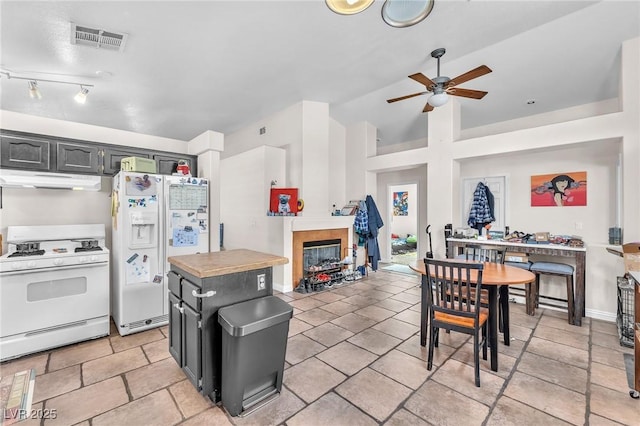 kitchen featuring visible vents, a ceiling fan, white appliances, extractor fan, and a tile fireplace