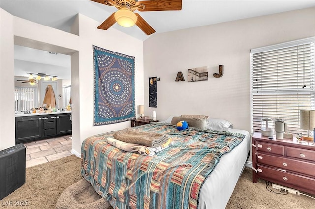 bedroom with a ceiling fan, light colored carpet, baseboards, and ensuite bathroom