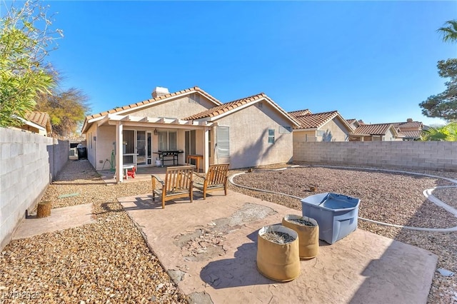 rear view of property with a tiled roof, stucco siding, a fenced backyard, and a patio area