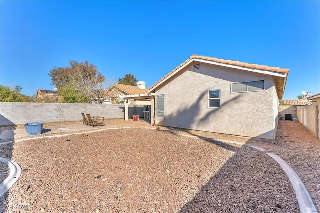 rear view of house with stucco siding, a patio, a tile roof, and a fenced backyard