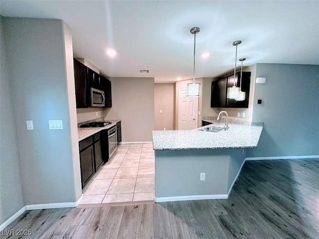 kitchen featuring kitchen peninsula, light hardwood / wood-style flooring, sink, appliances with stainless steel finishes, and pendant lighting