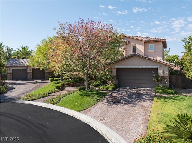 mediterranean / spanish house with decorative driveway, stone siding, a tile roof, and stucco siding