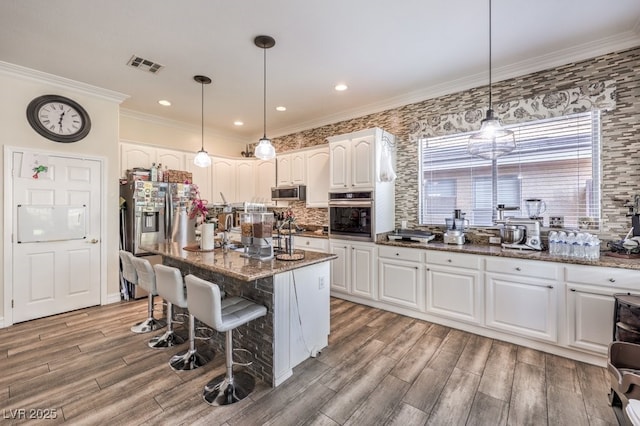 kitchen featuring a center island, hanging light fixtures, dark stone counters, appliances with stainless steel finishes, and white cabinets