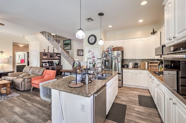 kitchen featuring white cabinetry, dark stone countertops, stainless steel appliances, and decorative light fixtures