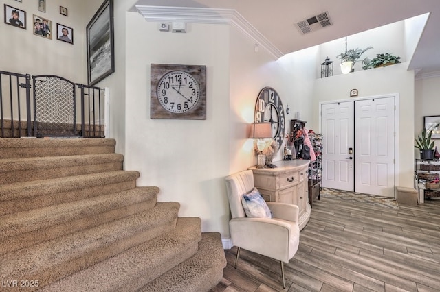 foyer entrance featuring crown molding, wood-type flooring, and a towering ceiling