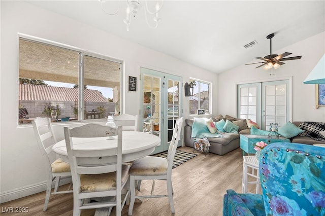 dining room with light hardwood / wood-style floors, french doors, and vaulted ceiling