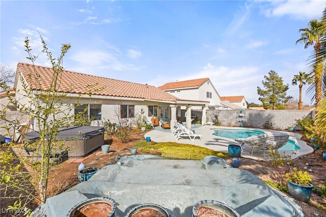 rear view of property with a patio area and a swimming pool with hot tub