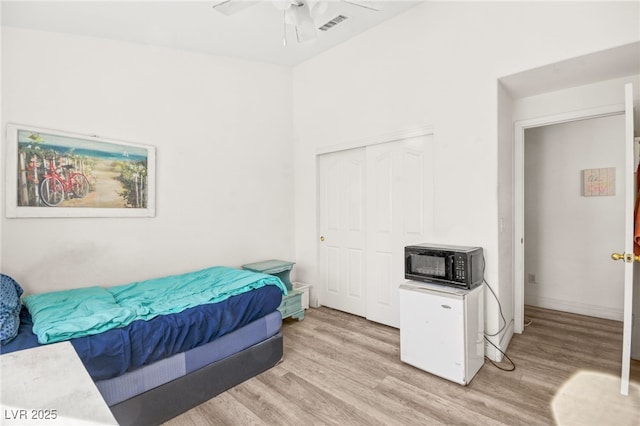 bedroom featuring light hardwood / wood-style flooring, ceiling fan, and a closet