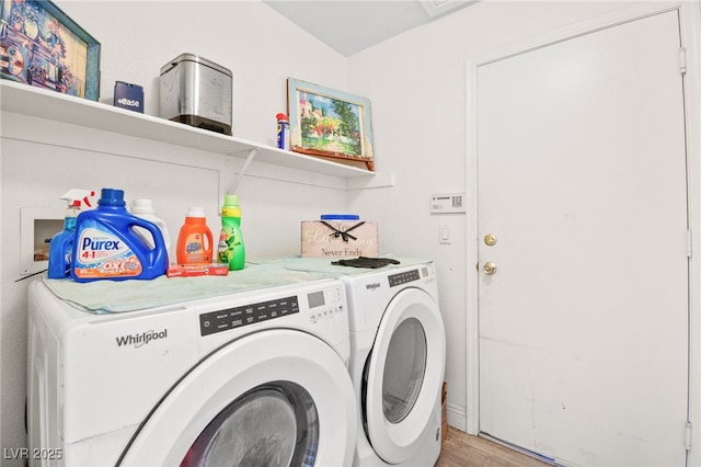 clothes washing area with washing machine and dryer and light hardwood / wood-style flooring