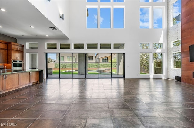 unfurnished living room featuring sink and a towering ceiling